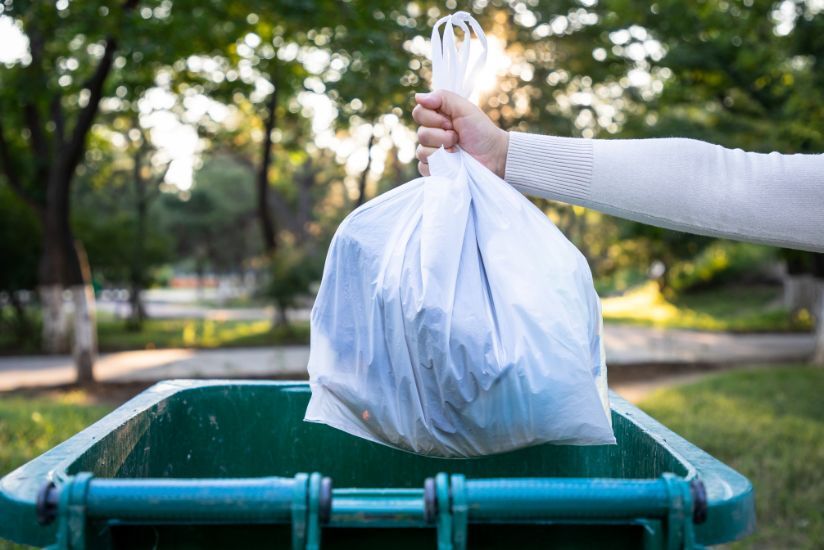 trash bag held over trashcan